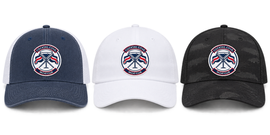 Navy and white trucker, white dad hat, and black camo trucker with the Cocktail Cove Yacht Club badge, side by side
