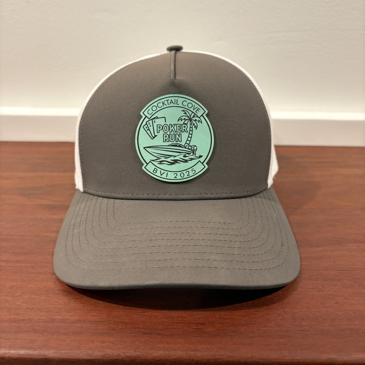 Custom hat example: charcoal and white trucker hat with a seafoam Cocktail Cove BVI Poker Run 2025 patch